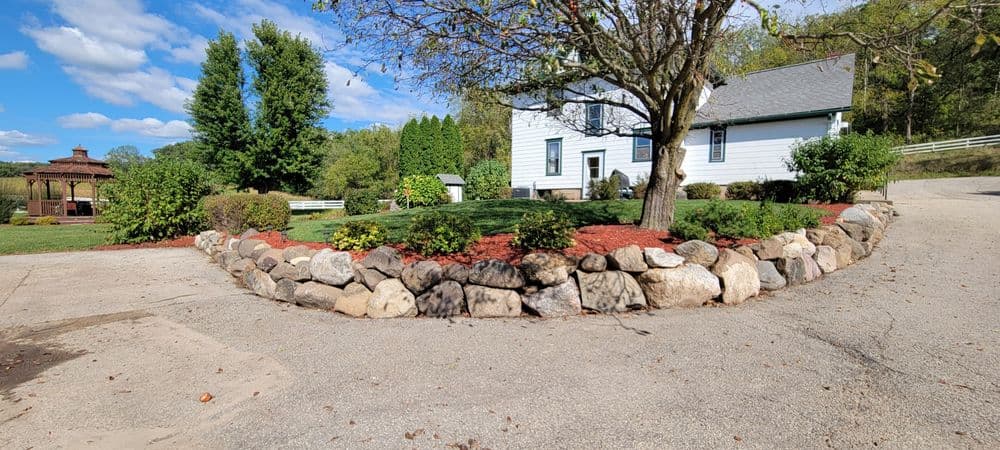 Scenic house with landscaped garden, stone border, and blue sky in background.