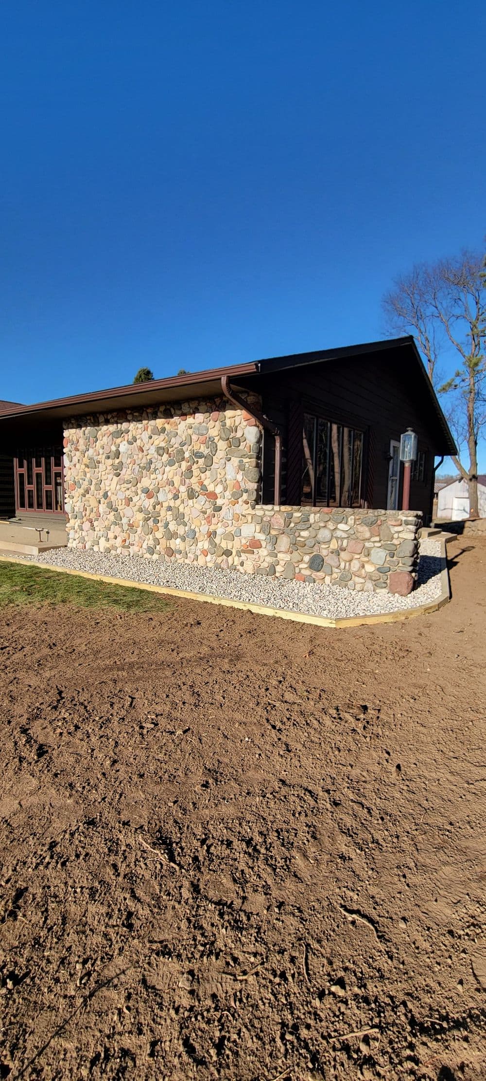 Charming stone exterior of a modern house with a clear blue sky background.